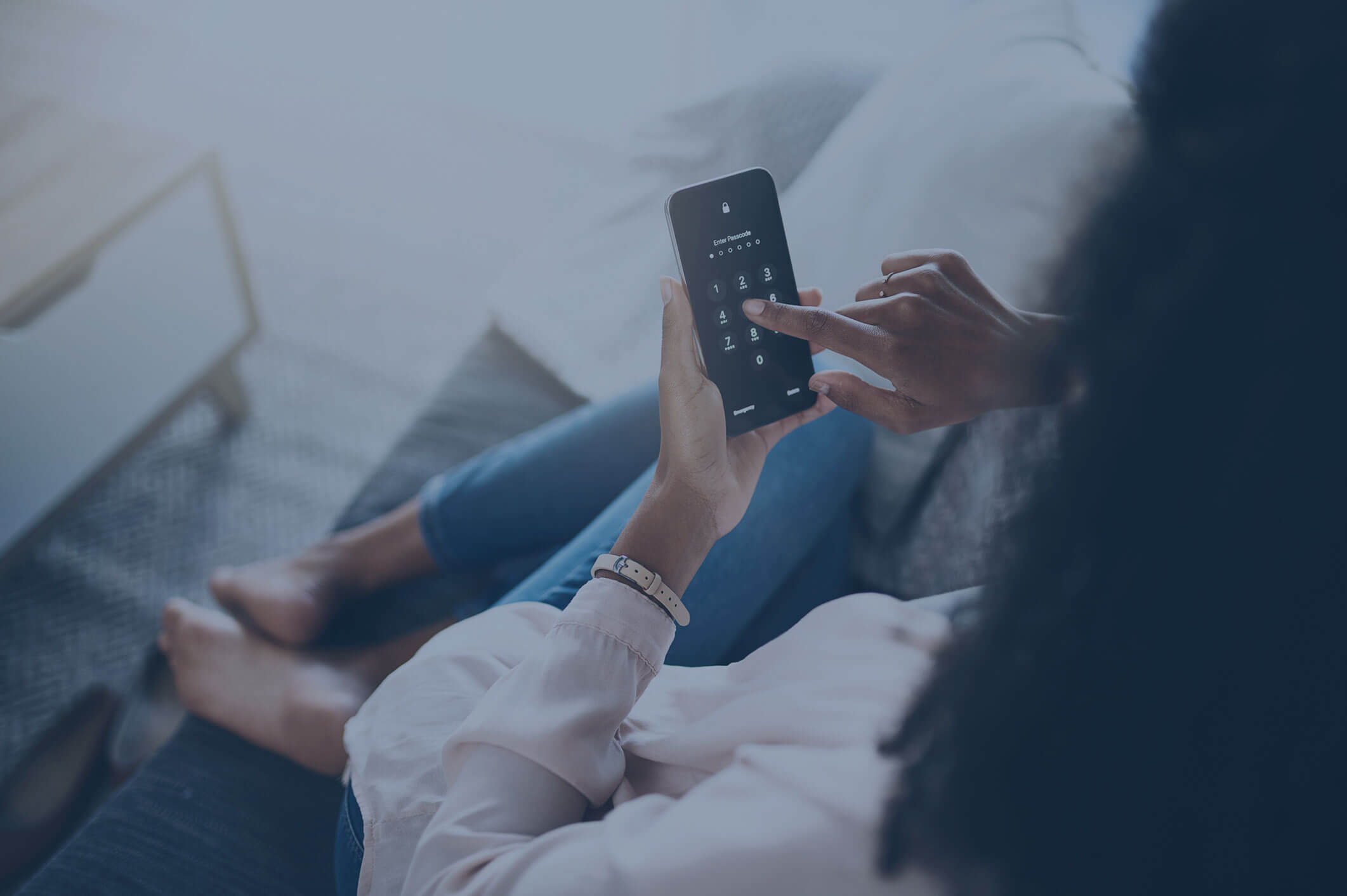 A woman relaxing on a couch and typing in her mobile phone password.