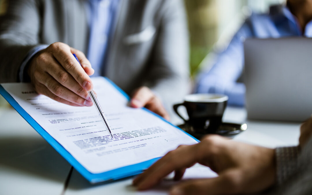 A business professional points to a document as he talks to another man.