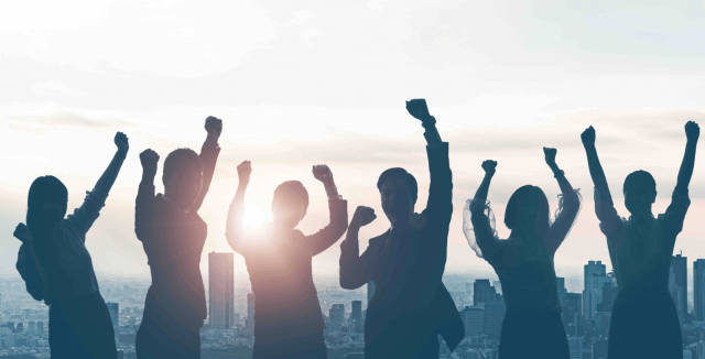 3 women and 3 men with raised hands in celebration. A city sklyine is in the background.