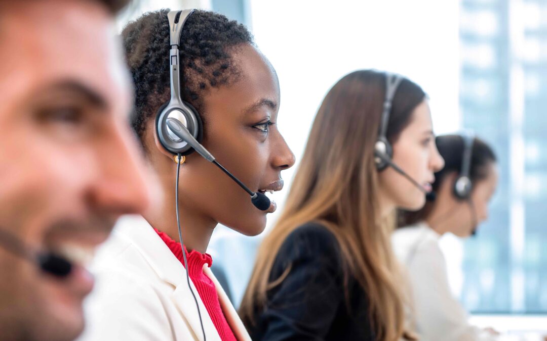 Call center agents wearing headsets and looking a computer screens.