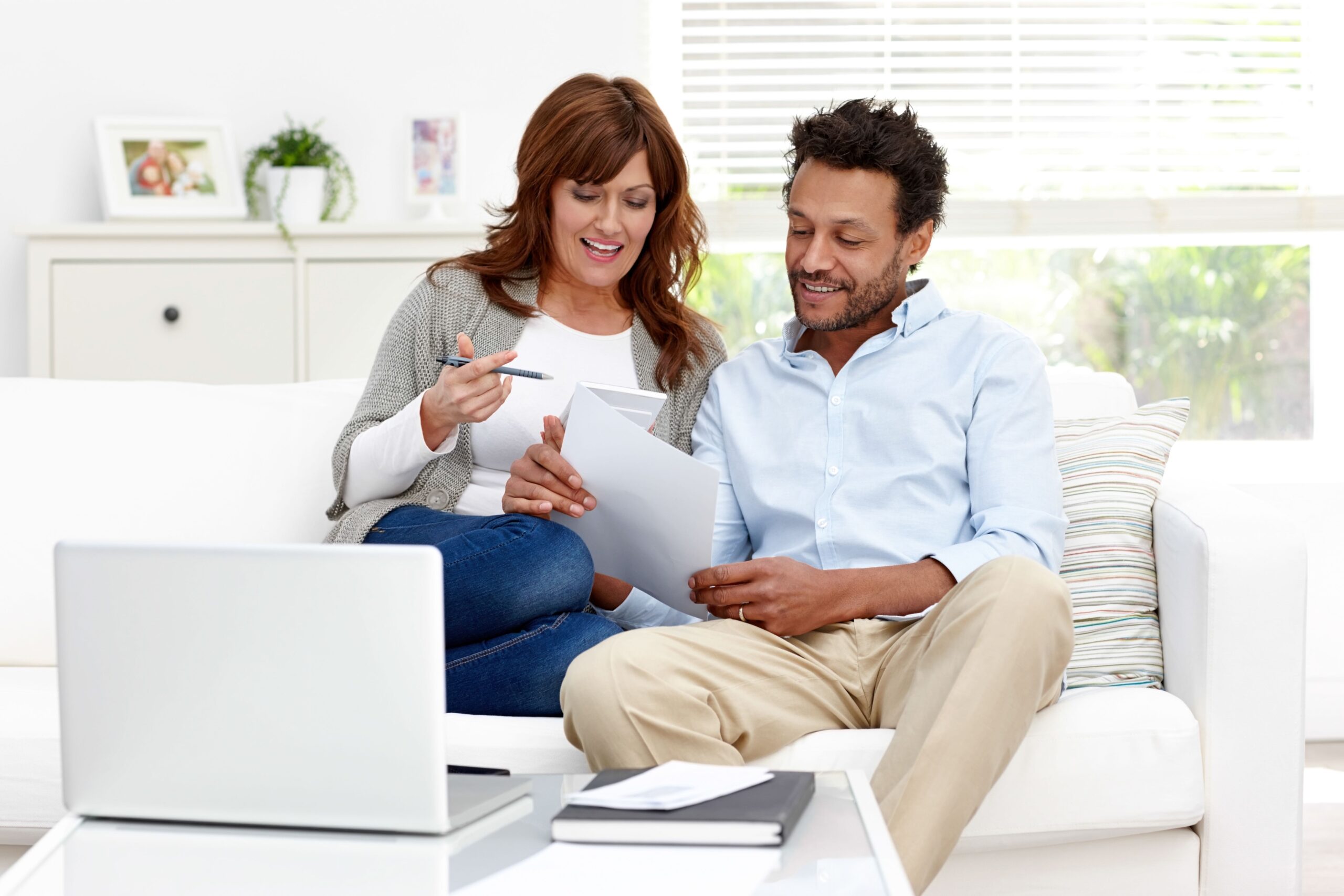 Man and woman sitting together on sofa calculating monthly expenses