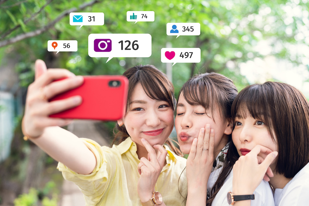 3 young woman smiling for phone camera and creating social media posts.