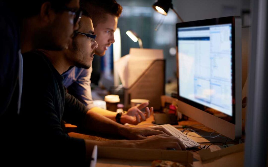 3 men looking at private data on a computer monitor.