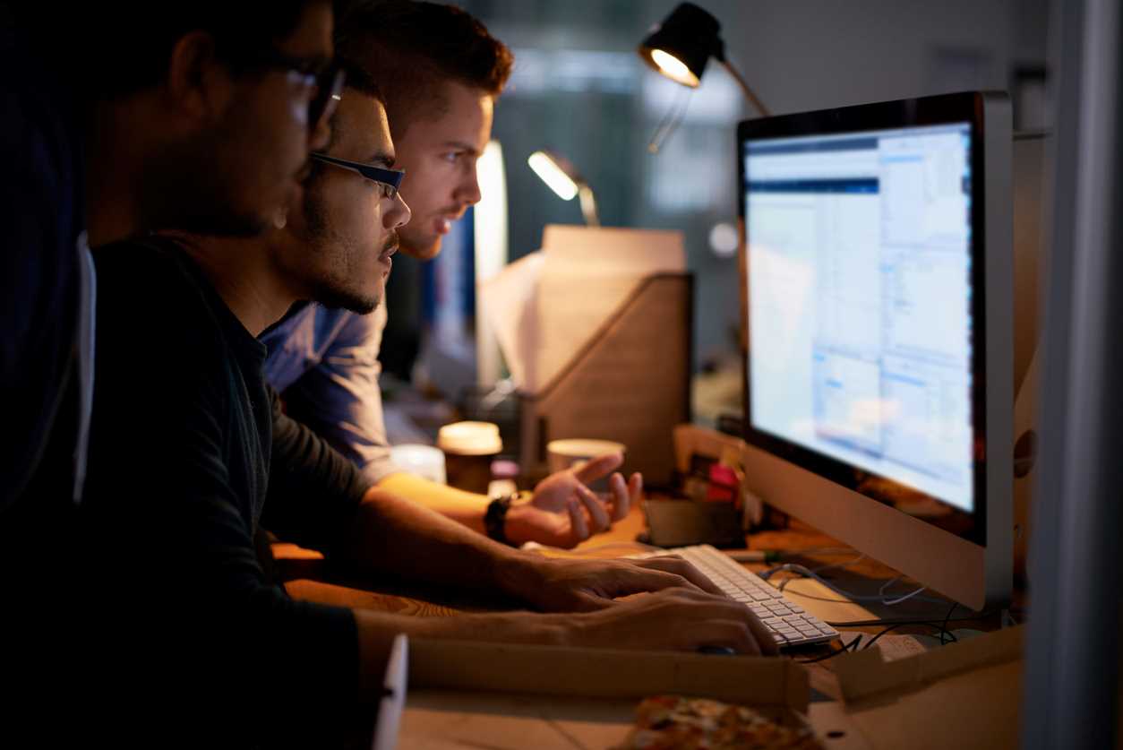 3 men looking at private data on a computer monitor.