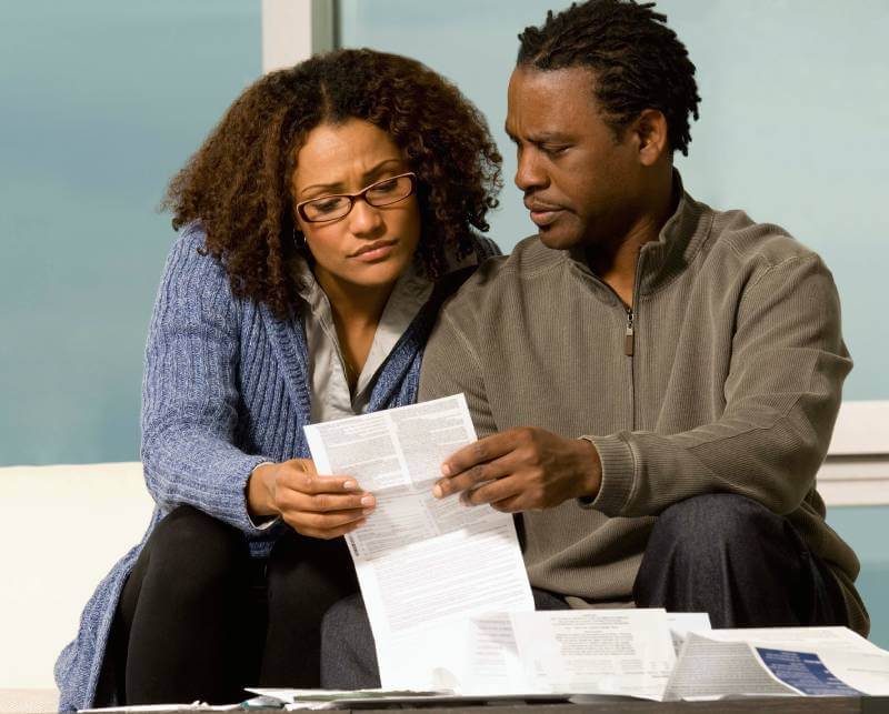 Couple reviewing their home title while looking concerned.