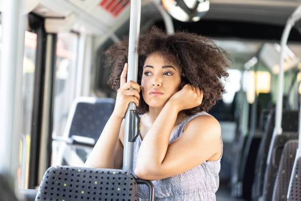 Sad woman on an airport shuttle bus experiencing a travel scam.