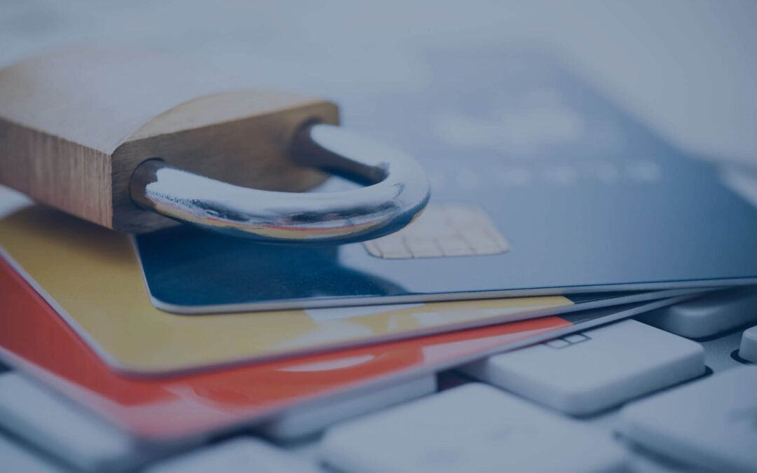 A padlock sits on top of credit cards sitting on a computer keyboard.