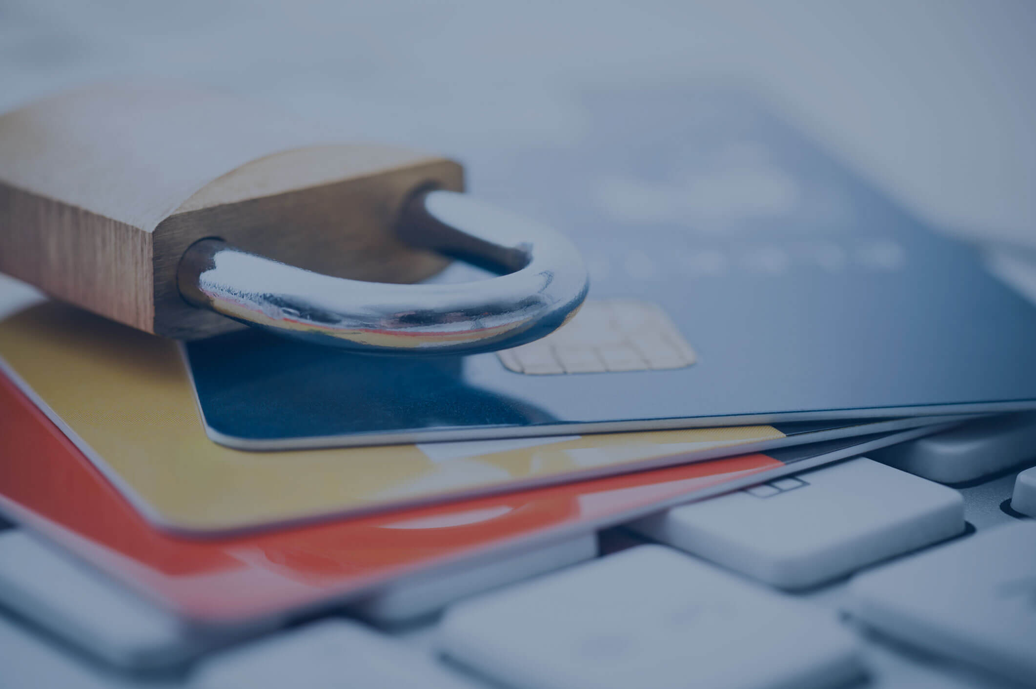 A padlock sits on top of credit cards sitting on a computer keyboard.