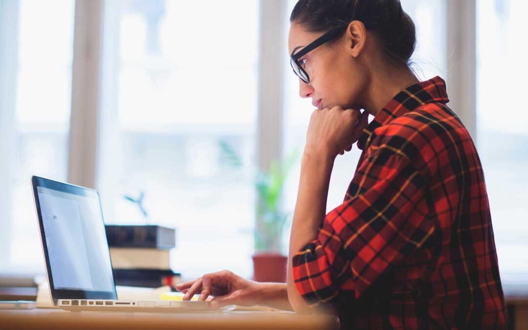 Woman seated at a desk navigating a laptop with her fingers.