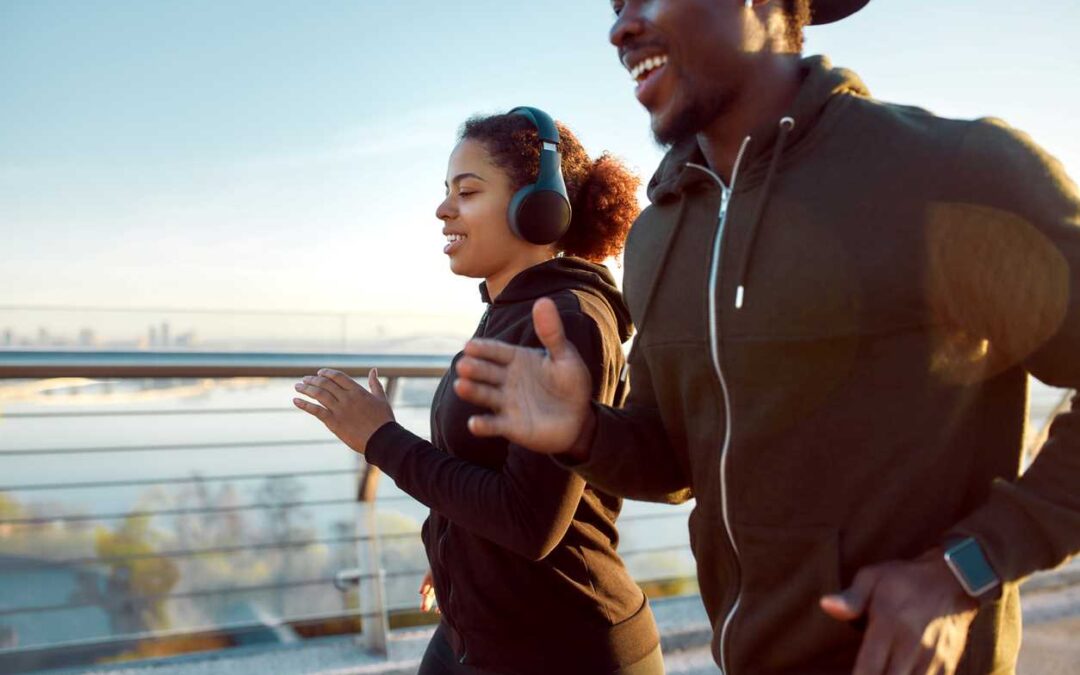 A young man and woman jogging together along a city path.