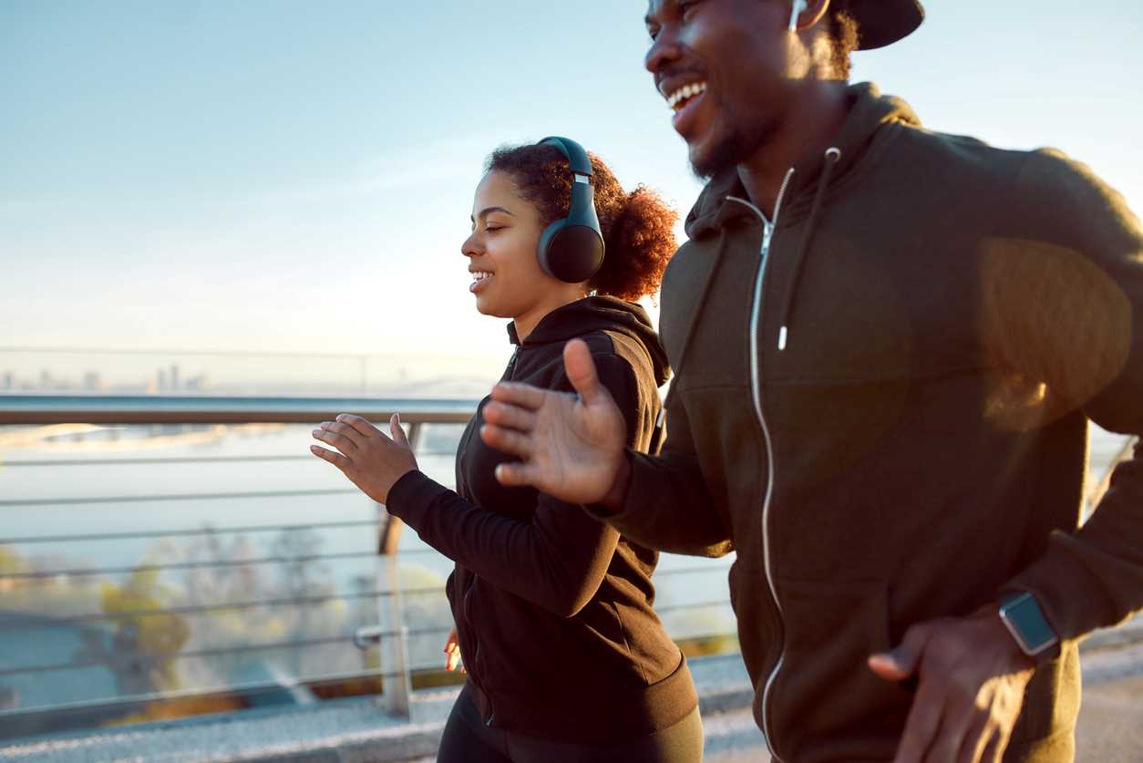 A young man and woman jogging together along a city path.