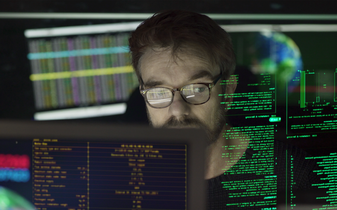 Man looking a various computer screens full of code.