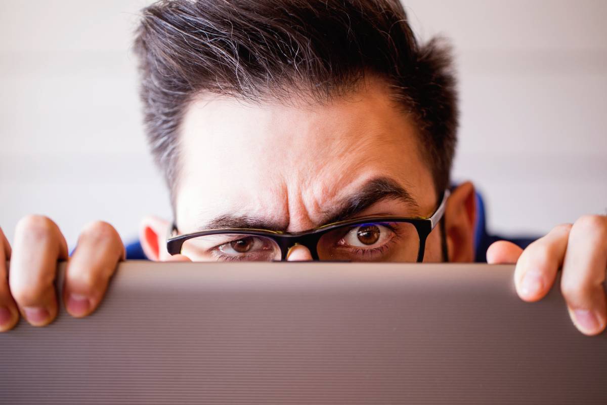 Man peeking up from top of laptop screen