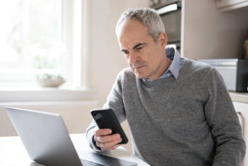 Mature mans seeing signs his phone has been hacked.