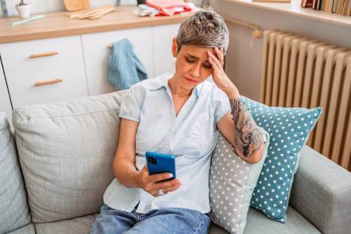 Worried woman looking at her phone with signs it has been hacked.