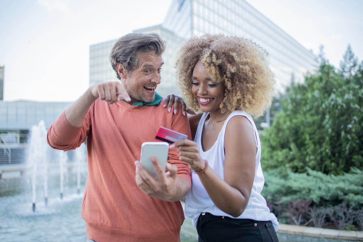 Happy couple looking at Facebook on a mobile phone.