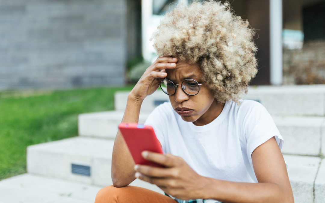 Mixed race young female looking worried and stress while reading bad news on her mobile phone.