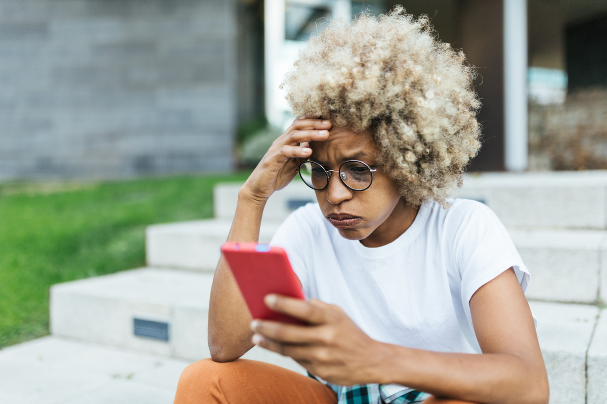 Mixed race young female looking worried and stress while reading bad news on her mobile phone.