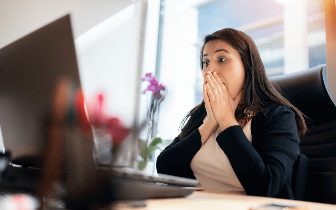 Woman sitting in front of her desktop computer and shocked to realize her email account has been hacked.