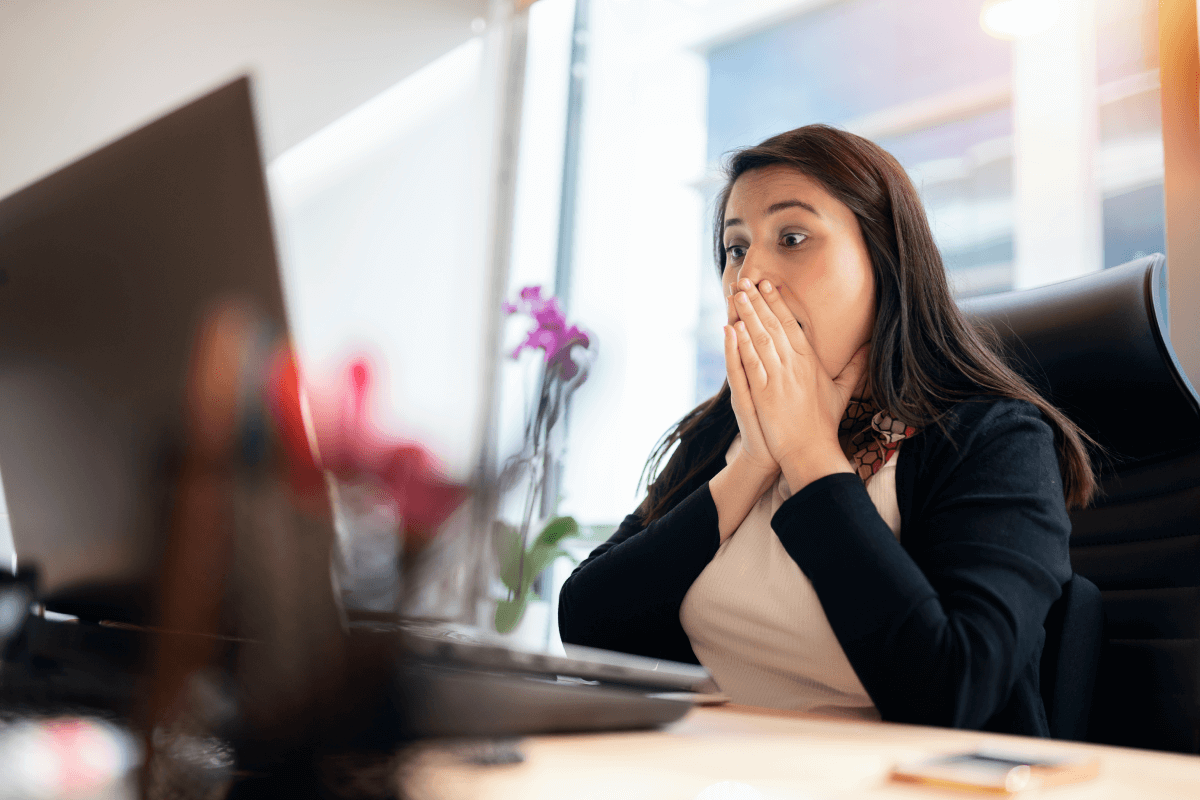 Woman sitting in front of her desktop computer and shocked to realize her email account has been hacked.