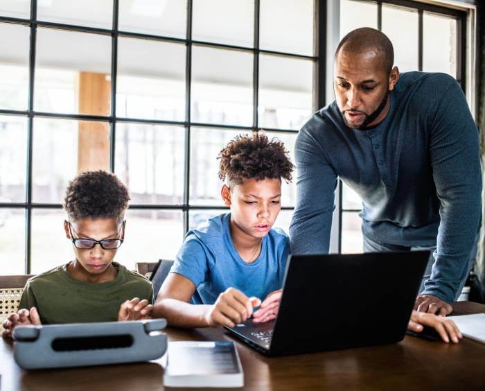 Man helping two young boys with a social media cleanup of their accounts.