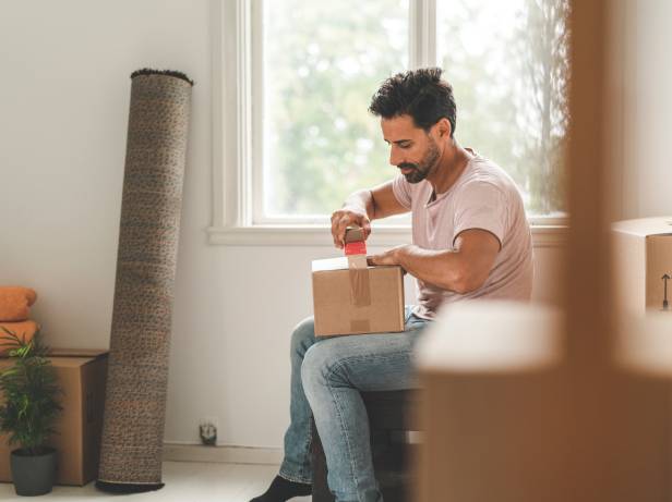 Man taping a home moving box.