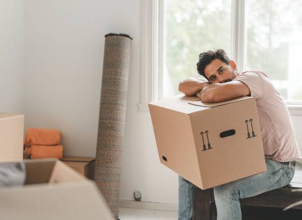 Man holding a home moving box and sad because of possible moving scams.