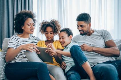 Mother, father, daughter and son viewing a digital device.