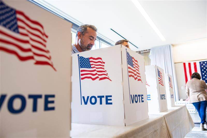 U.S. election booths containing voters at a voting center.